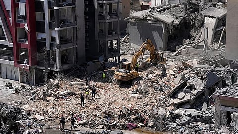 Rescue workers use an excavator, as they search for victims under the rubble of a building.