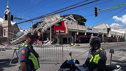 Police gather in front of a collapsed Jollibee fast food restaurant