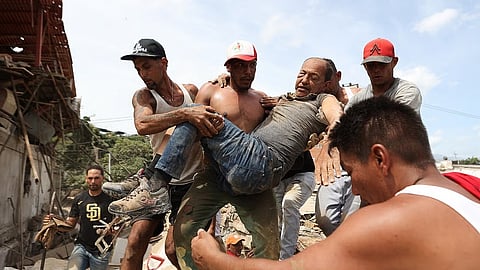 Neighbors carry a man rescued from the rubble of a collapsed building the day after earthquakes struck La Guaira, Venezuela, Thursday.