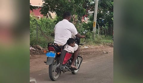 The child seated inside the side bag of a motorcycle in Gadag.