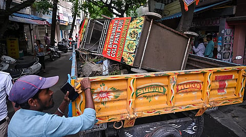 A vendor's pushcart is loaded onto a municipal vehicle during a footpath clearance drive.