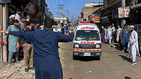 A volunteer clears the way for an ambulance transporting injured school children.
