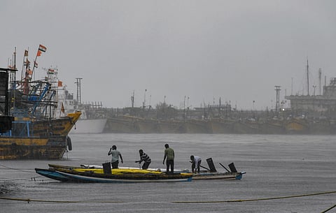 Fishermen secure their boats at a fishing harbour amidst heavy rain under overcast skies, ahead of severe cyclonic storm 'Arnab', in Visakhapatnam