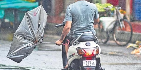 ಮುರಿದು ಹೋಗಿರುವ ಛತ್ರಿಯೊಂದಿಗೆ ದ್ವಿಚಕ್ರ ವಾಹನದಲ್ಲಿ ತೆರಳುತ್ತಿರುವ ವ್ಯಕ್ತಿ