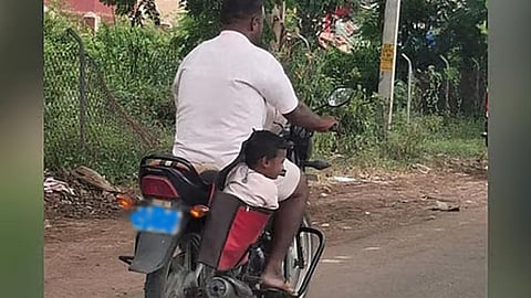மோட்டார்சைக்கிளின் பக்கவாட்டில் குழந்தையை பையில் வைத்து பயணித்த தந்தை