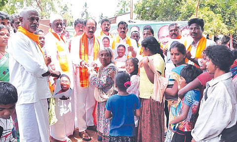 பா.ஜனதா தலைவர் சாமிநாதன் பழங்குடியினர் மக்களுக்கு சர்க்கரை வழங்கும் காட்சி.
