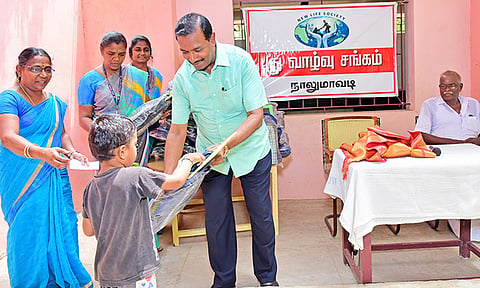 நாலுமாவடி தொடக்கப்பள்ளி மாணவன் ஒருவருக்கு இலவச சீருடைகள், புத்தக பைகள் ஆகியவற்றை மோகன் சி. லாசரஸ் வழங்கிய காட்சி.