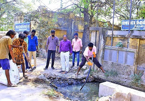 சுகாதார அலுவலர் இளங்கோ முன்னிலையில் மாவட்ட கல்வி அலுவலகம் முன்பு தேங்கி கிடந்த சாக்கடை கழிவுகள் வெளியேற்றப்பட்ட காட்சி.