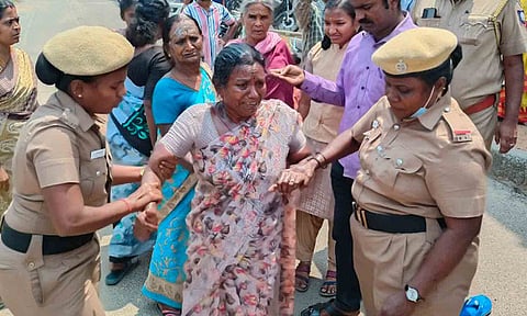 ஜான்சி தீக்குளிக்க முயன்றதையும் போலீசார் தடுத்து நிறுத்தியதையும் படத்தில் காணலாம். 