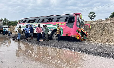 சாலை ஓர பள்ளத்தில் சுற்றுலா பஸ் கவிழ்ந்து இருப்பதை படத்தில் காணலாம்.