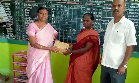 பள்ளித் தலைமை ஆசிரியர் நூலகப் பொறுப்பாசிரியரிடம் புத்தகம் வழங்கிய காட்சி. 