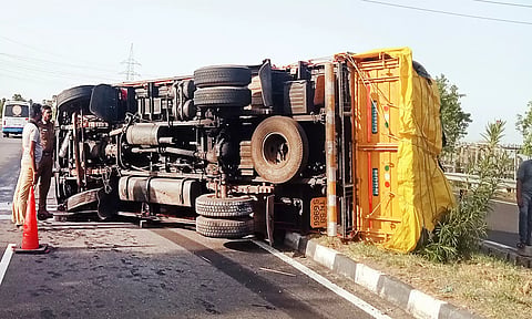 தலைகுப்புற கவிழ்ந்த லாரியை படத்தில் காணலாம்.