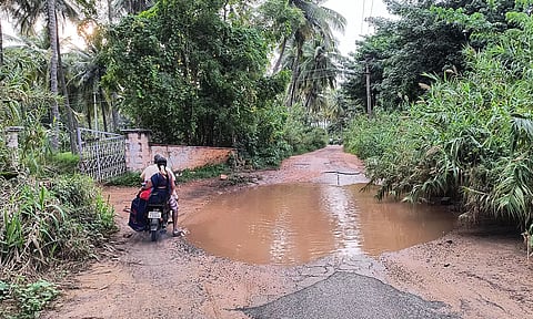 பள்ளத்தில் மழை நீர் தேங்கி உள்ளதால் தடுமாறிச்செல்லும் வாகன ஓட்டி.