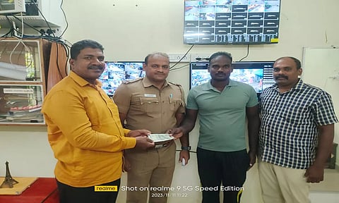 போலீசார் மணிபர்சை உரியவரிடம் ஒப்படைத்த காட்சி.