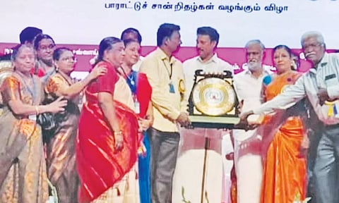 அமைச்சர் அன்பில் மகேஷ் பொய்யாமொழியிடம் தலைமையாசிரியர் பாலமுருகன் பரிசை பெற்றார்.
