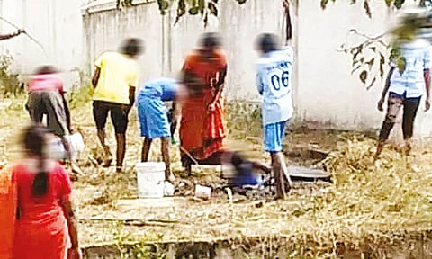 பள்ளியில் உள்ள கழிவறை தொட்டியை மாணவர்களை கொண்டு சுத்தம் செய்ய வைத்த காட்சி.