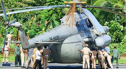 Security personnel push away a helicopter with low tires