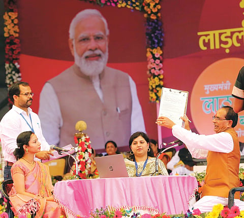 Chief Minister Shivraj Singh Chouhan helps a beneficiary to fill her form for granting Rs 1,000 per month during the launch of Ladli Behna Yojna
at Jamboree ground in Bhopal on Sunday.