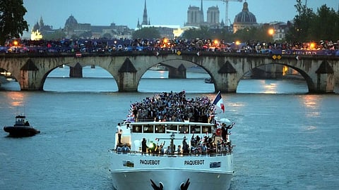 Athletes of France wave flags as they ride in a boat along the Seine River amid rain during the opening ceremony of the 2024 Summer Olympics, in Paris, France, Friday, July 26, 2024.