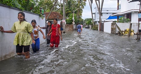 People wade through a flooded street after a sea storm lashed coastal areas, in Kochi, Monday, June 16, 2025.