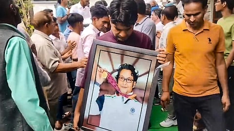 A man holds a portrait of legendary Indian pistol shooter and coach Jaspal Rana during a tribute ceremony before his last rites, at his residence, in Dehradun, Uttarakhand, Saturday, June 13, 2026.