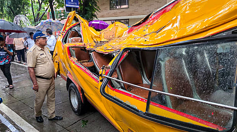A police official inspects a mangled school bus after a tree fell on it, in Chembur, Mumbai, Tuesday, June 30, 2026. An 11-year-old student was killed and four others were injured in the incident.