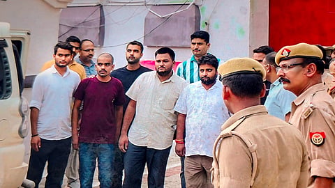 Police personnel escort three accused in the alleged Ram temple donation theft case after they were brought from jail on police custody remand, in Ayodhya, Wednesday, July 8, 2026.