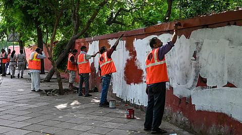 Delhi Municipal Corporation workers paint the graffiti-covered walls around Jantar Mantar on Sunday.