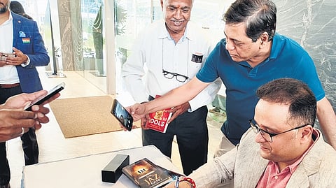 Author Amish Tripath signs a book as a man attempts to click a selfie at the inaugural plenary session of Hyderabad Literary Festival at Sattva Knowledge City on Friday