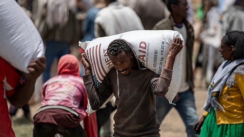 An Ethiopian man carries a sack of wheat on his shoulders to be distributed by the Relief Society of Tigray in the town of Agula, in the Tigray region of northern Ethiopia on May 8, 2021.
