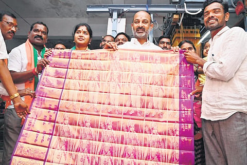 BJP general secretary Bandi Sanjay shows the gold saree weaved by V Hari Prasad