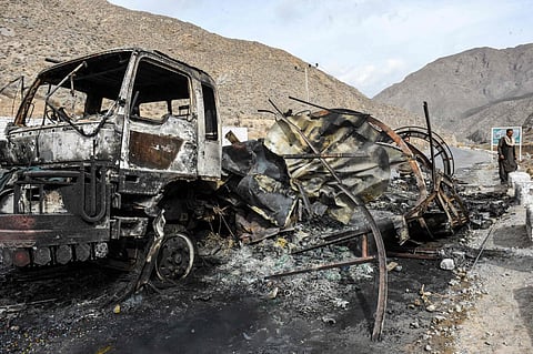 A man walks past a charred truck container torched by armed separatist group Balochistan Liberation Army (BLA) at central Bolan district in Balochistan province on January 30, 2024.