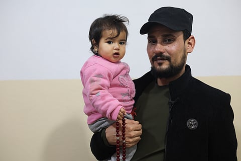 Khalil Al-Sawadi holds a one-year-old Afraa al-Sudani at his home in Jinderis, Syria.