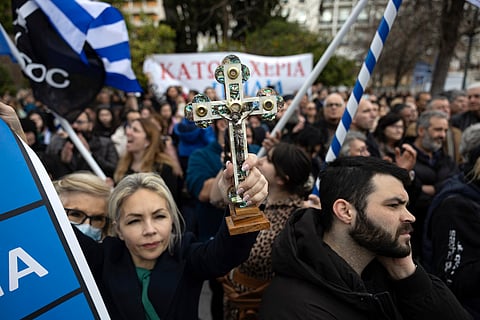 A protester raises a crucifix during a rally against same-sex marriage, at central Syntagma square, in Athens, Greece, Sunday, Feb. 11, 2024.