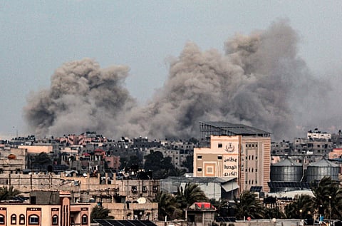 A picture taken from Rafah in the southern Gaza Strip shows smoke rising over buildings in Khan Yunis in the distance, following Israeli bombardment on February 5, 2024.