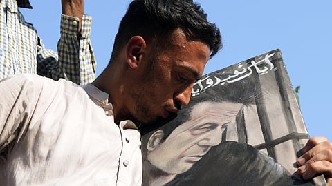A supporter of imprisoned Pakistan's former Prime Minister Imran Khan's kiss the portrait of his leader