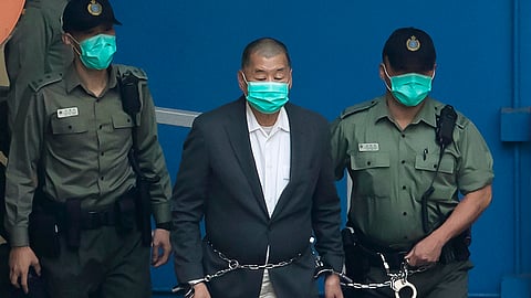 Jimmy Lai is escorted by Correctional Services officers to get on a prison van before appearing in a court in Hong Kong, Dec. 12, 2020.