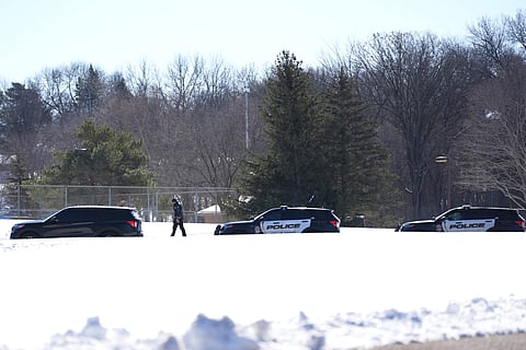 A police officer walks across a road after two police officers and a first responder were shot and killed Sunday, Feb. 18, 2024, in Burnsville, Minn.