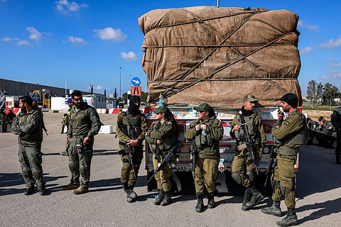 Israeli army soldiers stand by one of the Egyptian trucks bringing in humanitarian aid supplies to the Gaza Strip, on the Israeli side of the Kerem Shalom border crossing with the Palestinian territory on February 6, 2024