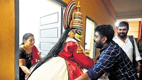 A participant dressed up in Kathakali costume has a hard time exiting the makeup room at the University College in Thiruvananthapuram