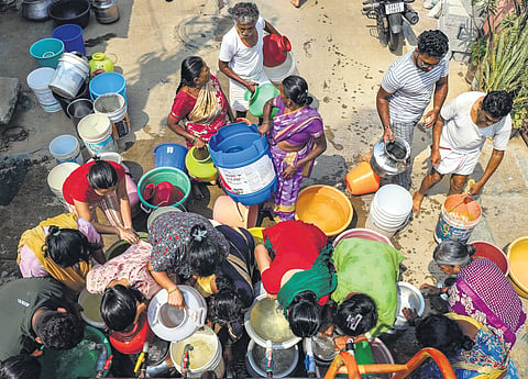 People collect free drinking water from a tanker at Bangarappa Nagar in Bengaluru on Sunday