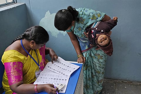 A woman searches for her name before casting her vote at a polling station during the Telangana state assembly elections in Hyderabad, Nov 30, 2023.