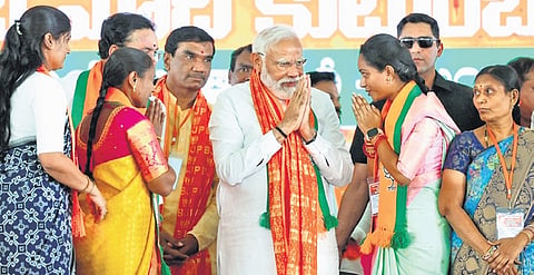 Prime Minister Narendra Modi greets women BJP activists in Jagtial on Monday