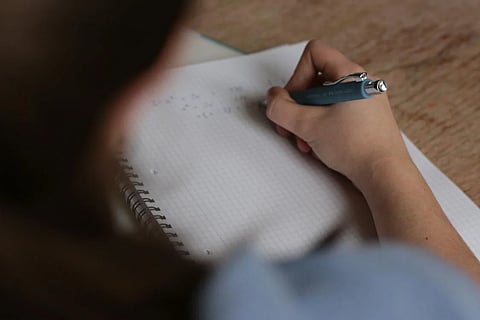 Image of a student writing an exam used for representational purposes only