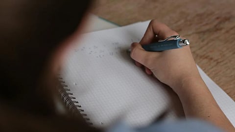 Image of a student writing an exam used for representational purposes only.