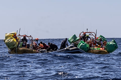 Migrants are helped evacuate a partially deflated rubber dinghy by the rescue personnel of the SOS Mediterranee humanitarian ship Ocean Viking in the Central Mediterranean Sea.