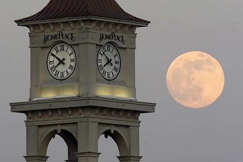 The moon rises behind the Home Place clock tower in Prattville, Ala., Saturday, June 22, 2013.