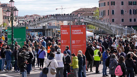 Stewards check tourists QR code access outside the main train station in Venice, Italy, Thursday, April 25, 2024.