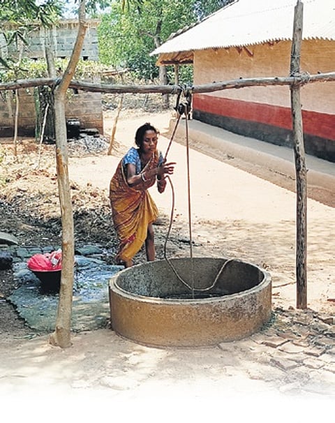 A woman of Chaksuliapada village drawing water from a well