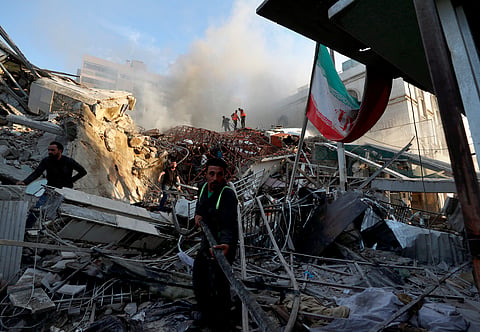 Emergency services work at a destroyed building hit by an air strike in Damascus, Syria, Monday, April 1, 2024.
